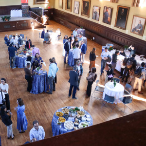 An aerial view of the 2026 Celebration of Research crowd. People mingle, talk, and eat with tables of food spread throughout the room. 