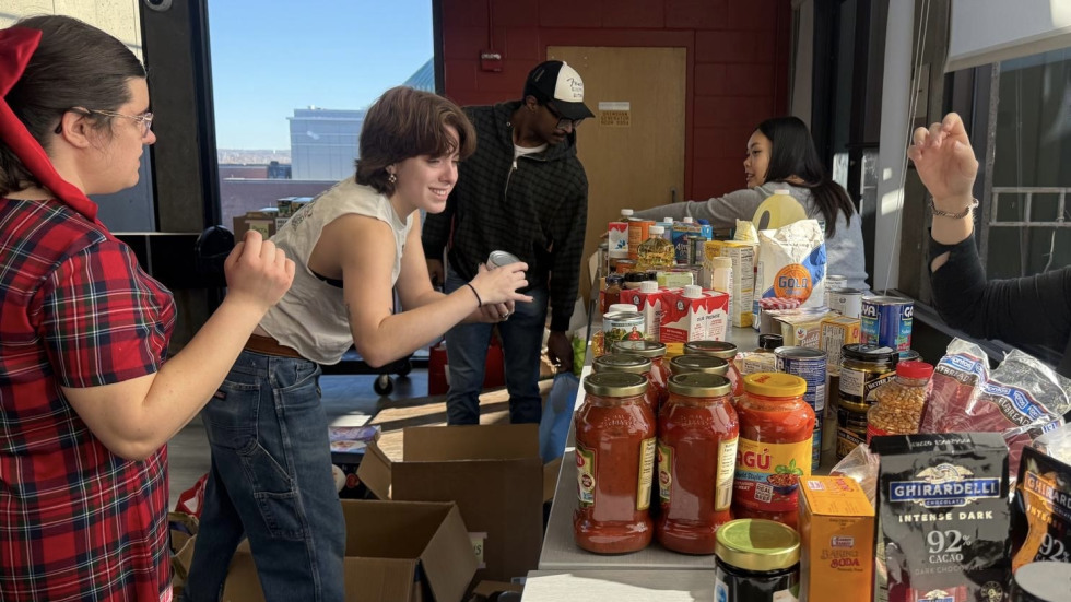 Students organize food items at a donation table.