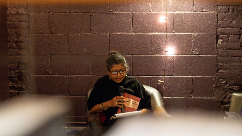 Zamindar reading, seen through a bookshelf.