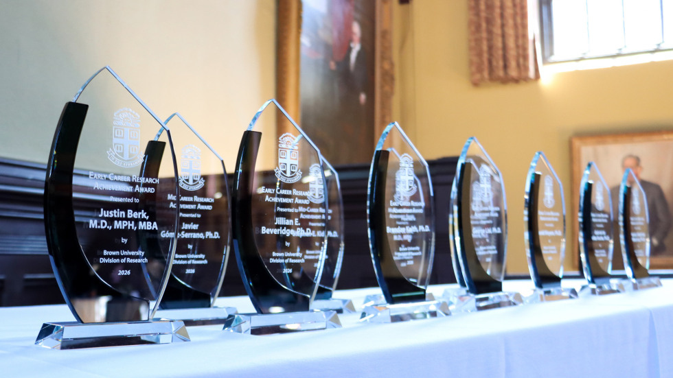 Research Achievement award trophies are lined up on a table.